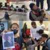 Kumala Elvira bersama Anaknya menunjukkan foto Presiden Prabowo Subianto saat mendatangi Pengadilan Negeri Sungguminasa, Gowa, Senin (24/8/2026). Istri terdakwa Ilyas Sitaba itu meminta perhatian pemerintah dan berharap suaminya memperoleh keadilan dalam perkara pencurian Tanah Timbunan yang tengah dituduhkan dan disidangkan.